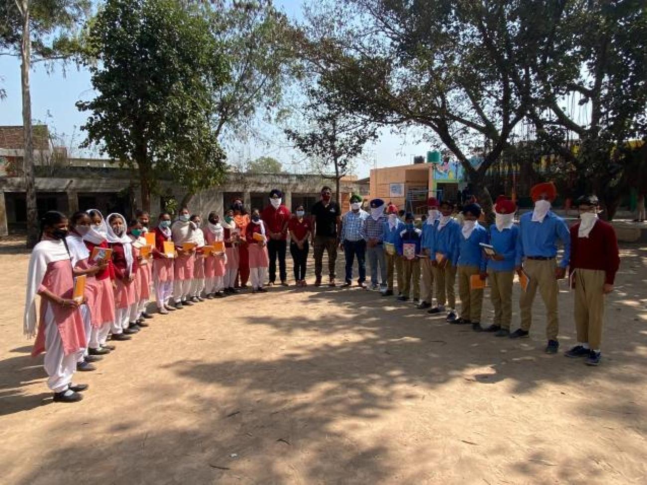 Volunteers from Chitkara University (center) pose with students of the government school in Tahu Village in the State of Punjab, India, during a book distribution event, part of the 3R Campaign 2030, 4 March 2021. Photo courtesy of Chitkara University.